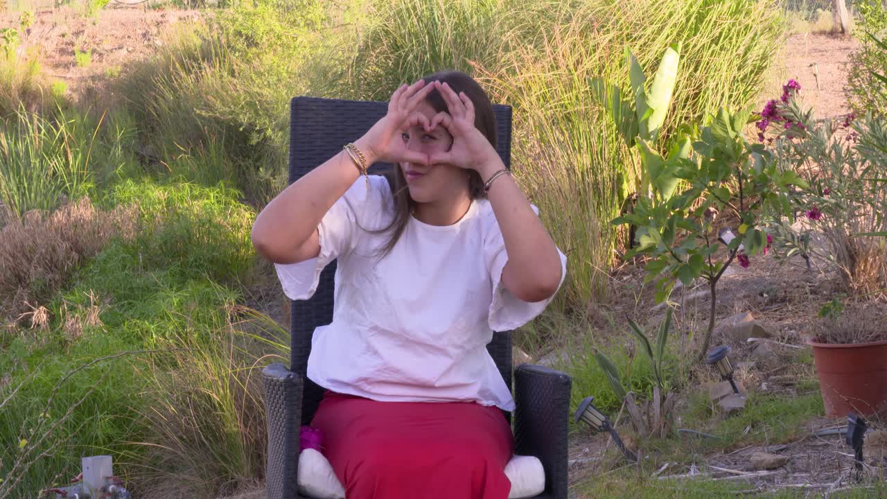 젊은 소녀는 그녀의 얼굴에 손 심장을 만들고