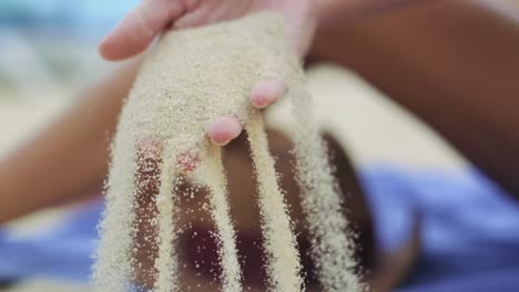 woman letting go on the sand from her hands in slow motion