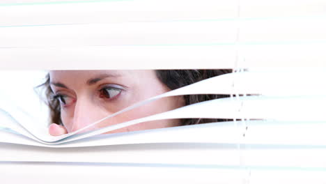 Woman-peering-through-roller-blind