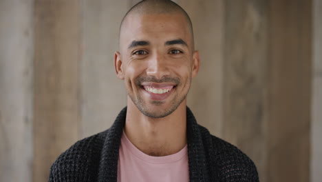 retrato de un joven hispano atractivo sonriendo disfrutando de un estilo de vida feliz mirando a la cámara con fondo de madera en cámara lenta