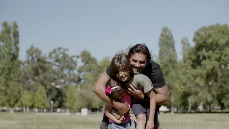 foto larga de papá con discapacidad abrazando a los niños en el parque