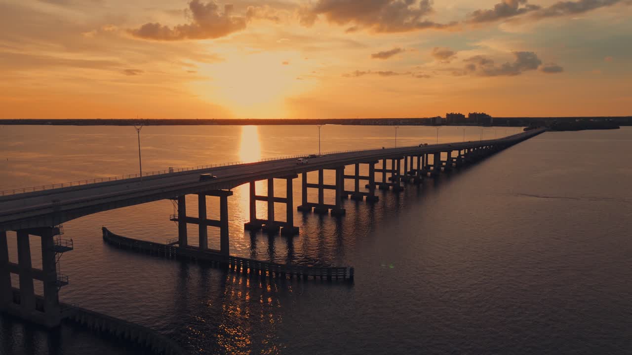 Silhouette of many vehicles on bridge over caloosahatchee river in fort Myers, Florida. Aerial tracking shot. Quiet evening scene. Wide shot