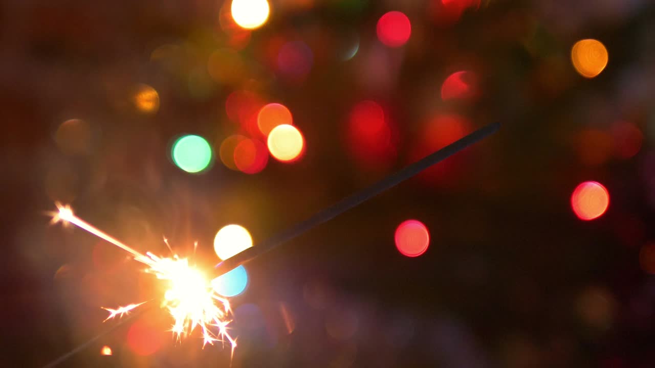 fuego de bengala ardiente y chispas en el fondo del árbol de navidad desenfocado en 4k cámara lenta 60 fps