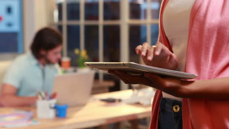 mujer de negocios casual usando la tableta delante de su colega
