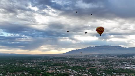 Heißluftballons-Schweben-über-Albuquerque,-Mit-Einem-Atemberaubenden-Blick-Auf-Die-Berge-Und-Bewölktem-Himmel,-Und-Präsentieren-Das-Berühmte-Ballonfest-Der-Stadt