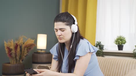 una mujer escuchando música con auriculares es infeliz y triste.