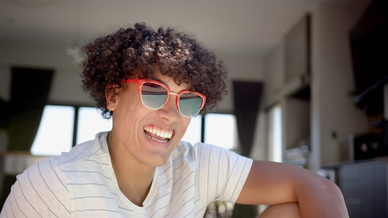 Smiling young man wearing sunglasses, relaxing at home in casual attire
