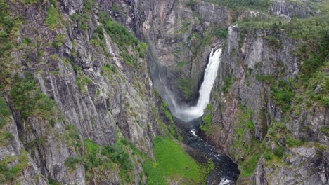 amazing vøringsfossen waterfall inside canyon - aerial moving backwards - huge amount of water falling down from mountain plateu hardangervidda - norway