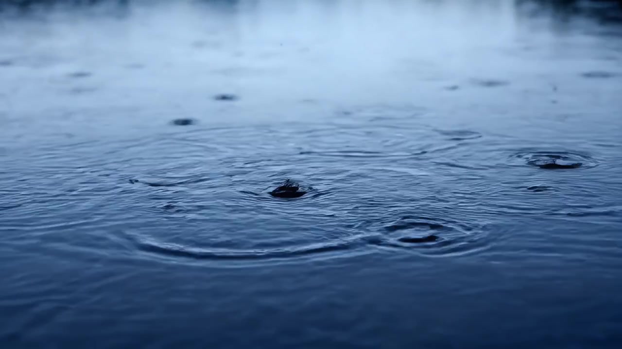 Raindrops Falling on Calm Dark Water Surface