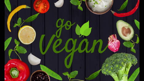 go vegan text over various fresh vegetables and herbs on dark background