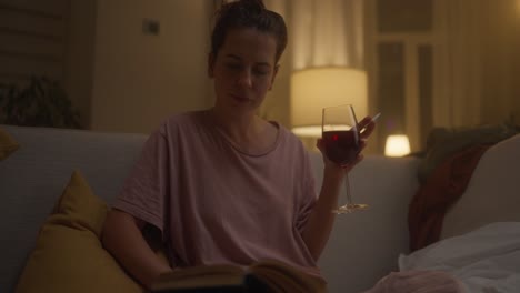 mujer leyendo y bebiendo vino por la noche
