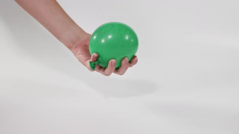 hand squeezing a green water balloon