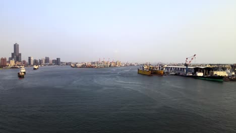 Flying-over-river-towards-large-ships-and-dock