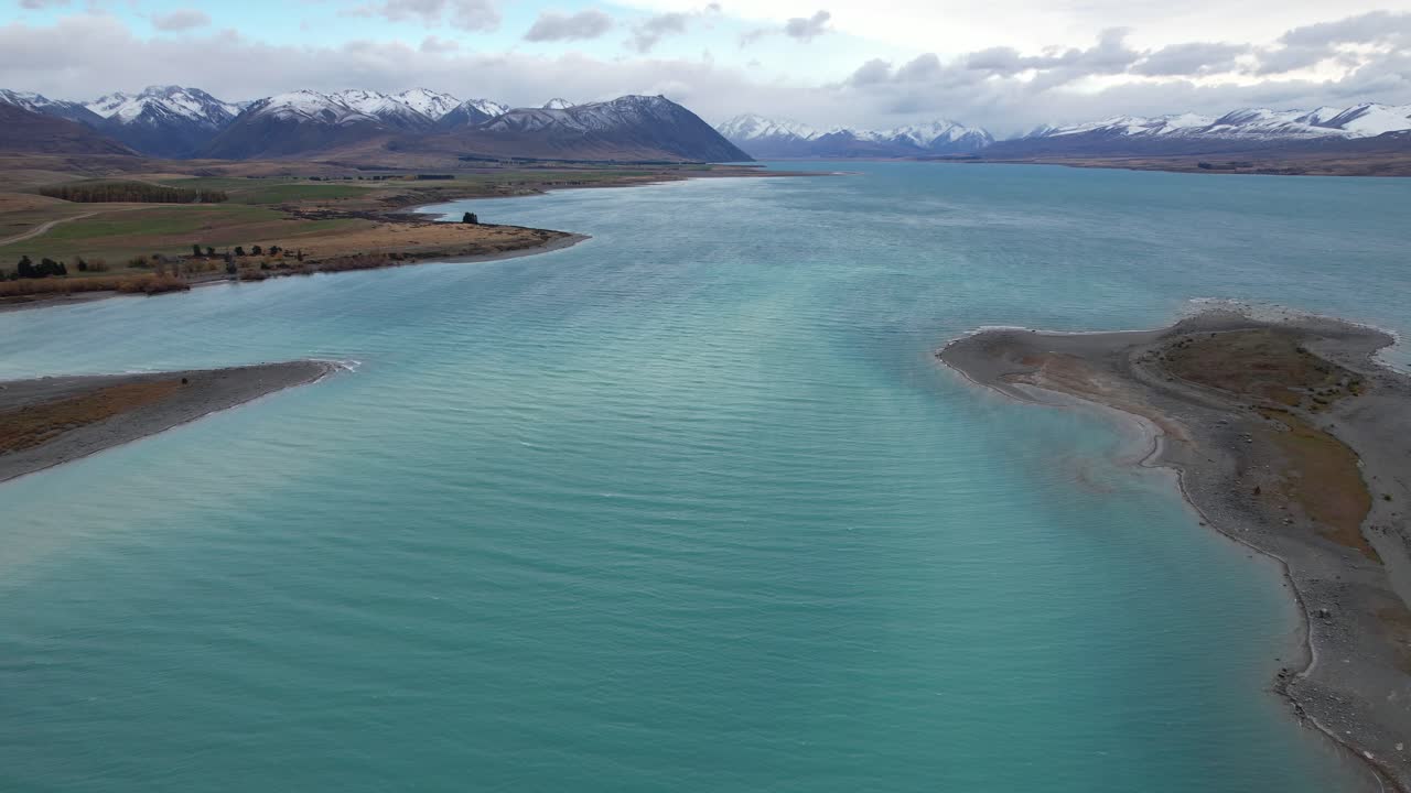 Stunning Turquoise Blue Waters Of Lake Tekapo With Mountain Views In South Island, New Zealand. - aerial shot