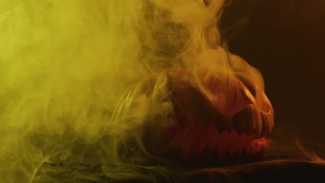 Video-of-halloween-carved-pumpkin-with-smoke-and-orange-light-on-black-background