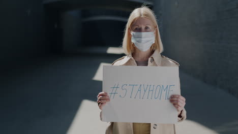 elderly woman wearing mask and holding a sign with the message #stayhome