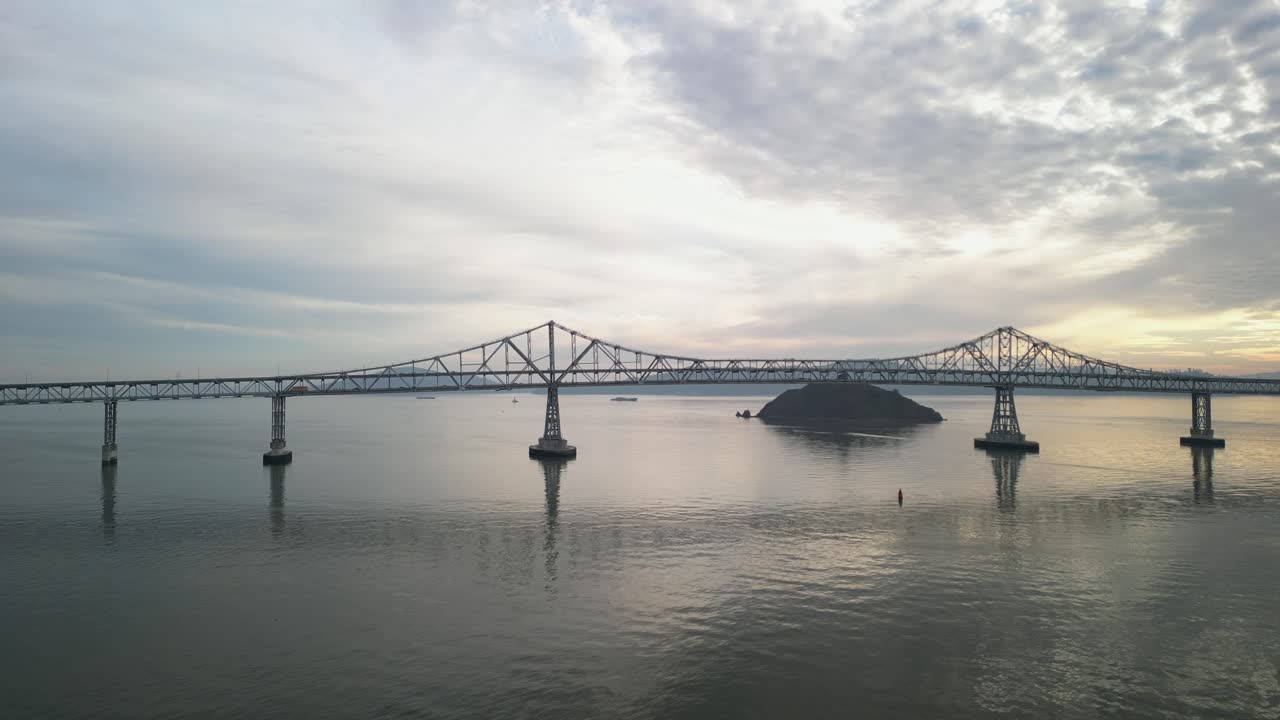 Aerial overview of Richmond Bridge from Point Molate Beach Richmond California USA, backlit with orange glow in corner reflecting on water