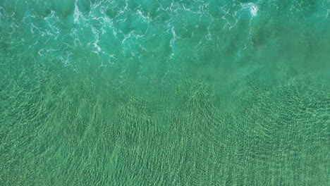 4k top view aerial shot of small tide waves close to the shore at byron bay, australia