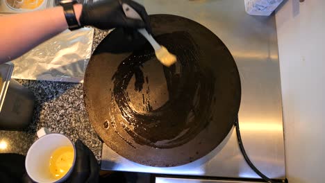 the chef greases the pan with oil for pancakes