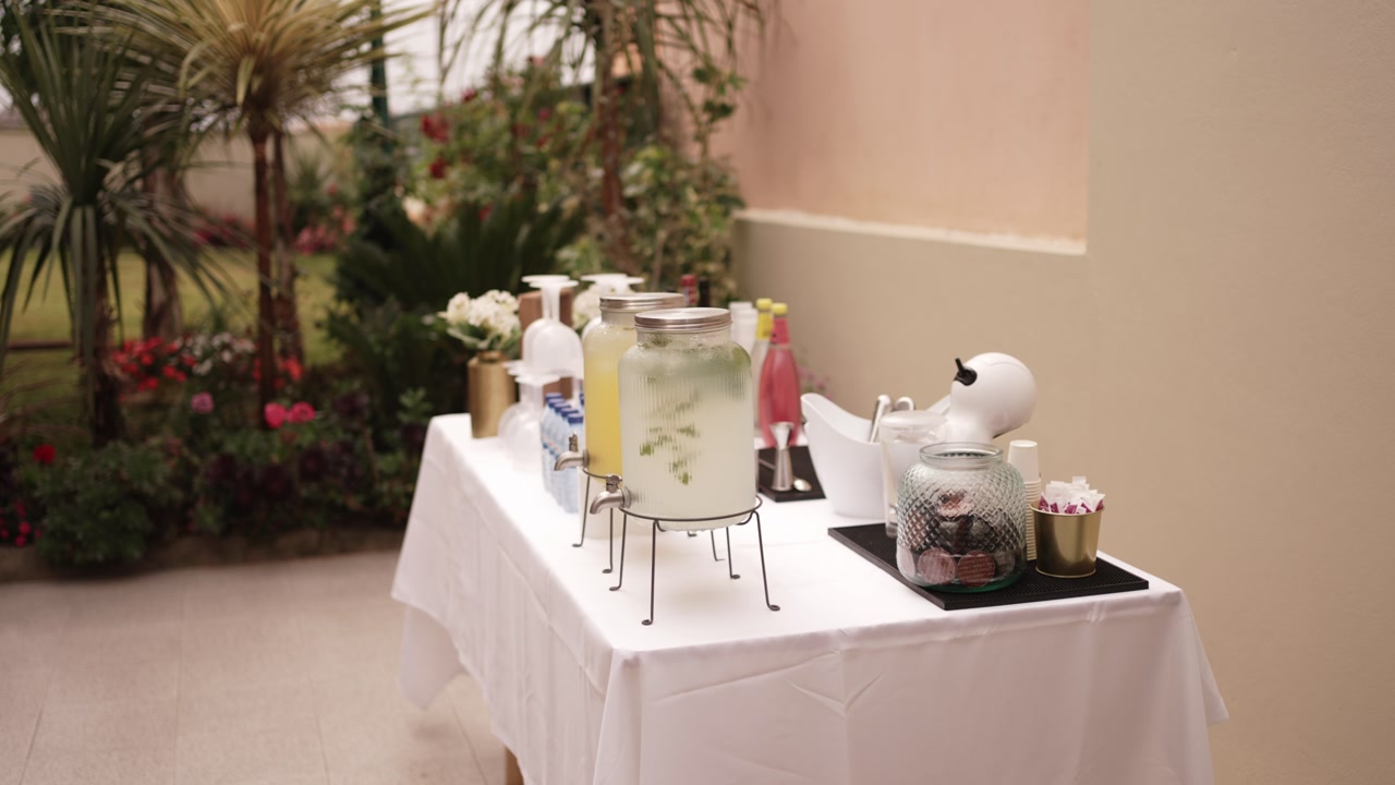 Table set with glass drink dispensers, cups, and sweets for a wedding reception