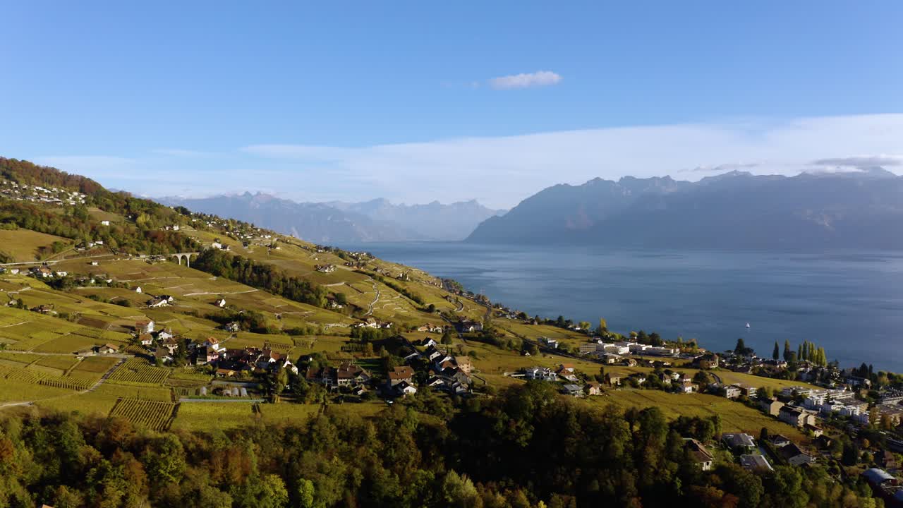 alto vuelo sobre el pueblo de savuit en el viñedo de lavaux, suiza, el lago leman y los alpes al fondo.