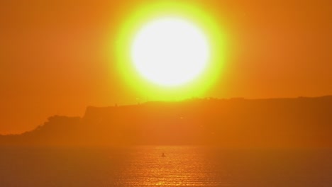 big glowing sun rising over calm seas, coastal seascape