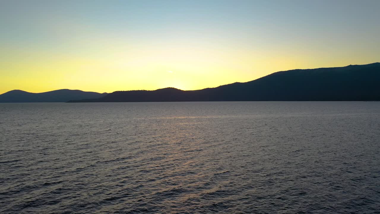 agua prístina ondeando en el lago mientras el sol sale sobre las montañas, drones aéreos volando a la hora dorada - lago tahoe en las montañas de sierra nevada, california con cielo brillante