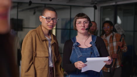 female film director and assistant watching actors and checking script shooting movie or video scene in studio 1