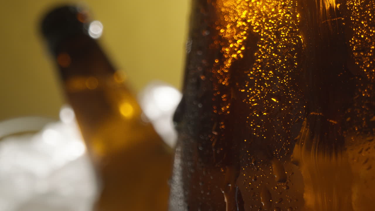 Close Up Of Condensation Droplets Running Down Glass Bottles Of Cold Beer Or Soft Drinks Chilling In Ice Filled Bucket Against Yellow Background 1
