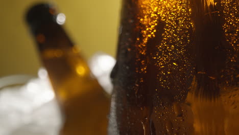 Primer-Plano-De-Gotas-De-Condensación-Corriendo-Por-Botellas-De-Vidrio-De-Cerveza-Fría-O-Refrescos-Enfriándose-En-Un-Cubo-Lleno-De-Hielo-Contra-Fondo-Amarillo-1