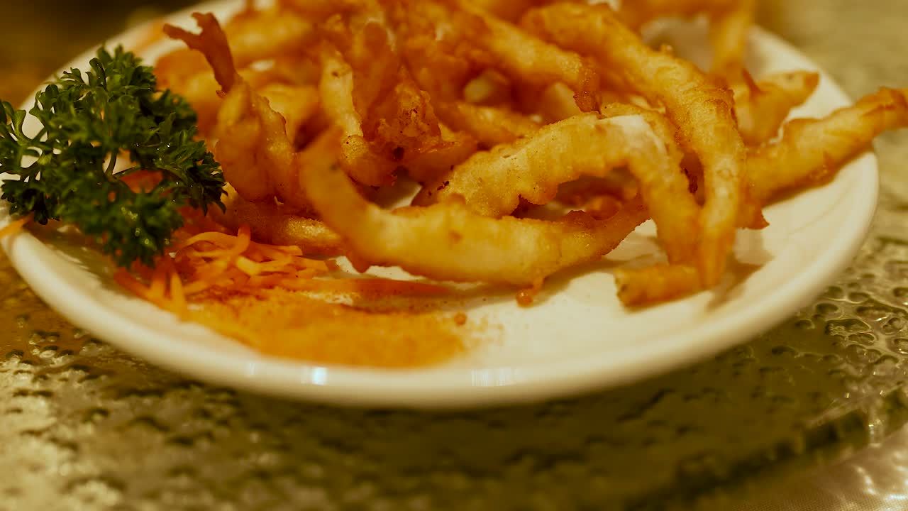 Plate of deep-fried snacks with garnish under warm lighting in a restaurant setting