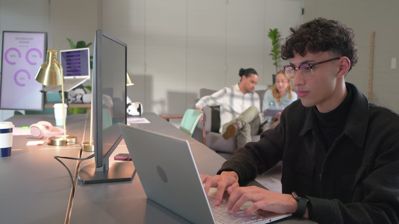 Diverse team seeing chat bubbles on monitor, male typing on laptop pair consulting tablet in office