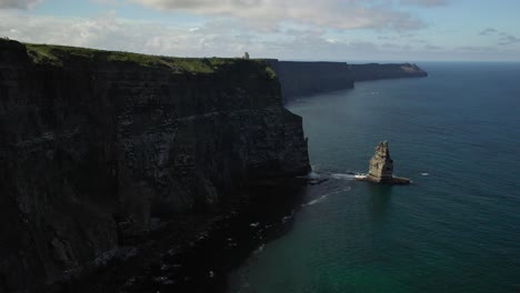 Sea-birds-flying-along-Cliffs-of-Moher-coastline,-Ireland,-aerial-pull-back