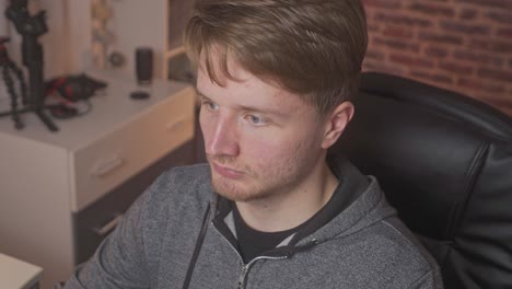 a youtube personality is setting at his desk, focuses on the computer screen intensely focuses and then leaves his desk