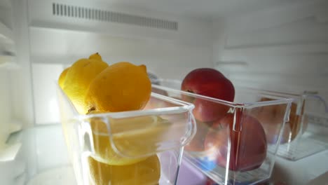 un refrigerador con limones y manzanas dentro