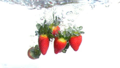 strawberries dropped into water in super slow motion