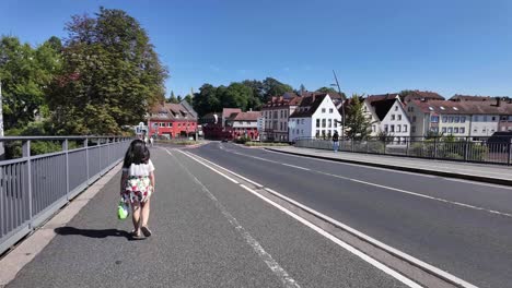 walking across the bridge to aschaffenburg centre of the town, behind a little girl with passing traffic. bavaria, germany, willigsbrucke