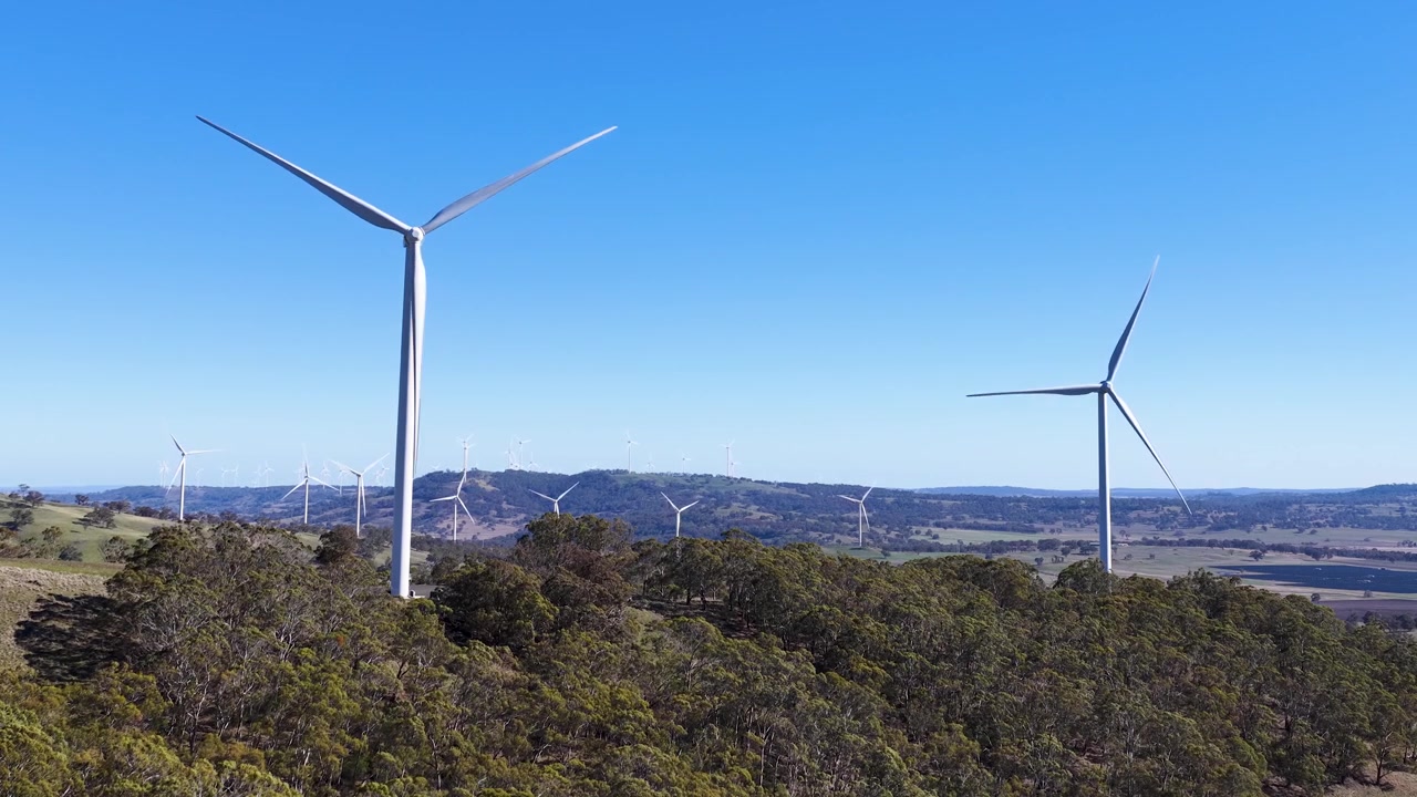 Tomada ampla de turbinas eólicas brancas gerando energia renovável em uma crista verde na Austrália.