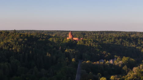 beautiful aerial ascend over a fairy tale like castle in the ancient forest of sigulda, latvia; historic landmark and tourist attraction.
