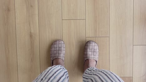 person in pajamas and slippers on a wooden floor