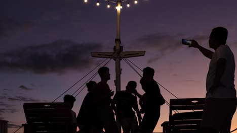 silhouette of people having fun and party on the boat deck during the sunset time.