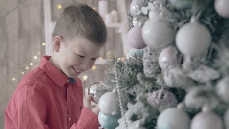 schoolboy enjoys watching reflection in christmas tree toy