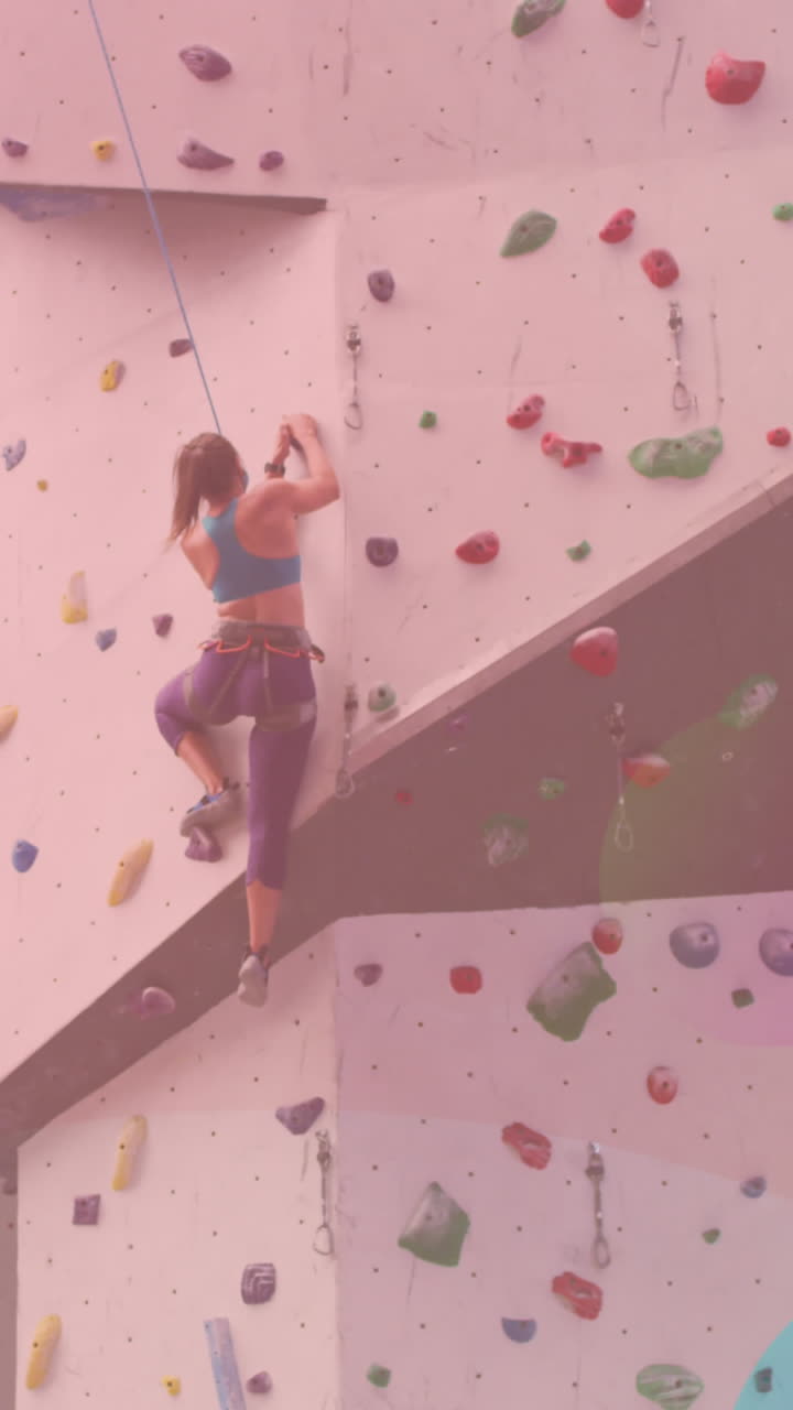 Forme astratte e colorate contro una donna caucasica in forma che fa arrampicata su parete in palestra