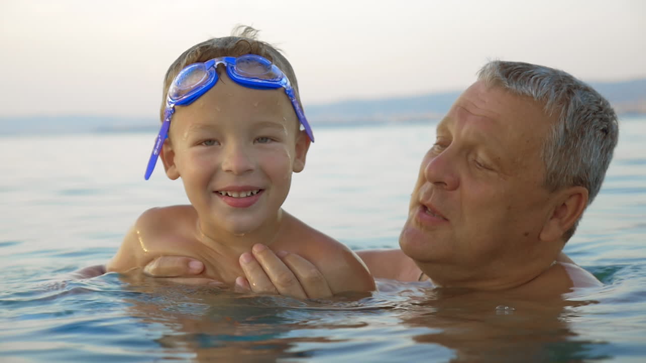 아이와 할아버지가 바다에서 목욕하고 있습니다.