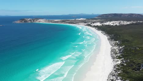 Excelente-Toma-Aérea-De-Automóviles-Lejanos-Que-Circulan-Por-Las-Arenas-Blancas-De-La-Bahía-De-Wharton-Mientras-El-Agua-Azul-Clara-Baña-La-Costa-En-Esperance,-Australia