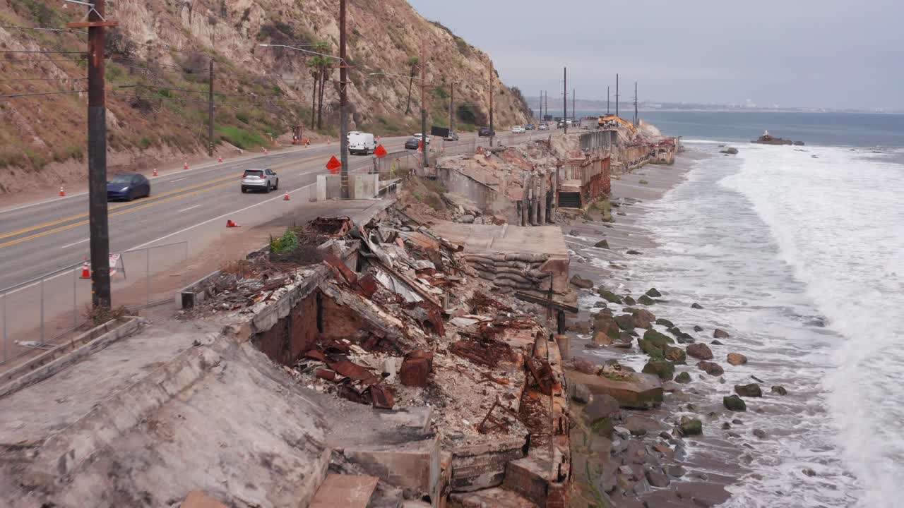 Aerial low shot flying over oceanfront residential lots burned by the Palisades Fire in Malibu, California. 4K