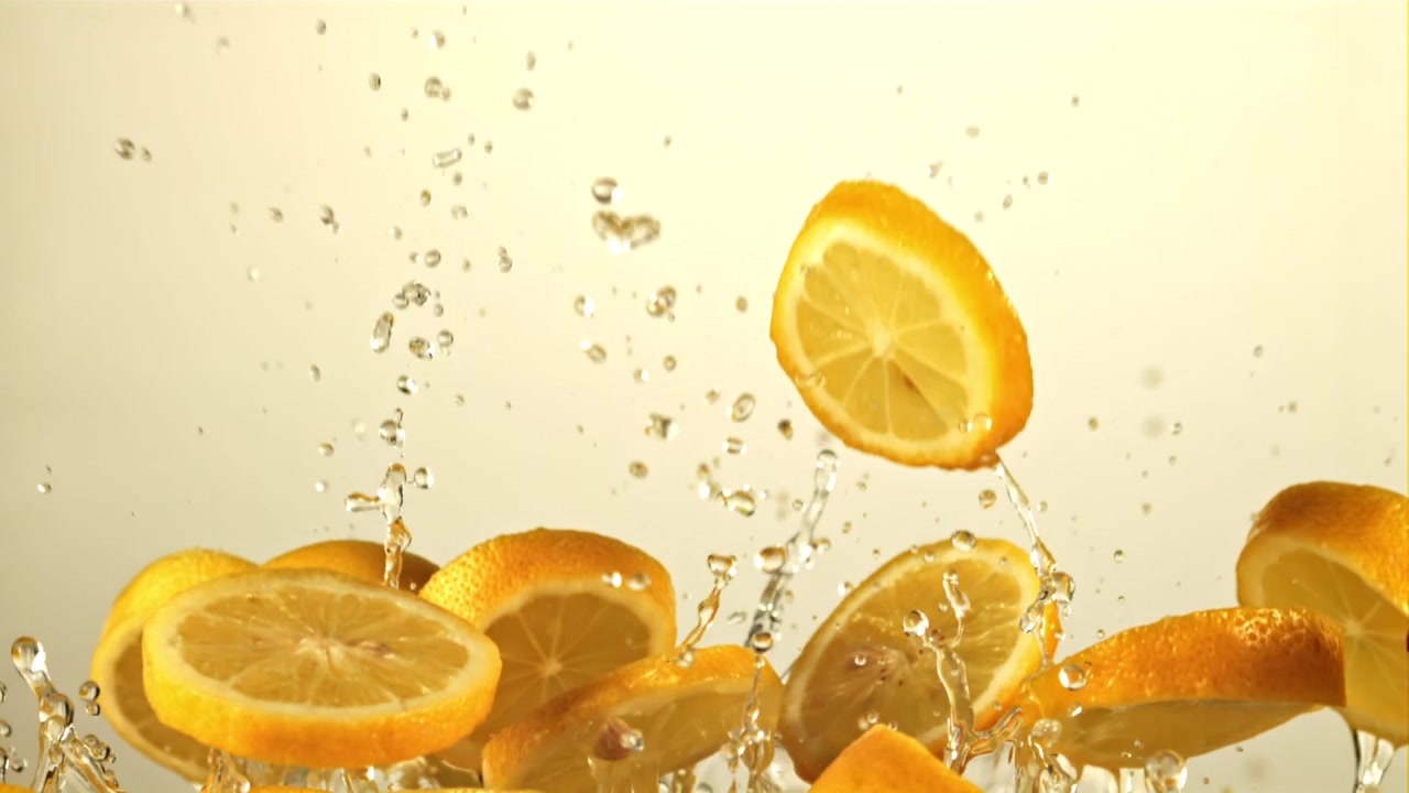 Frische Zitronenscheiben spritzen in Zeitlupe ins Wasser.