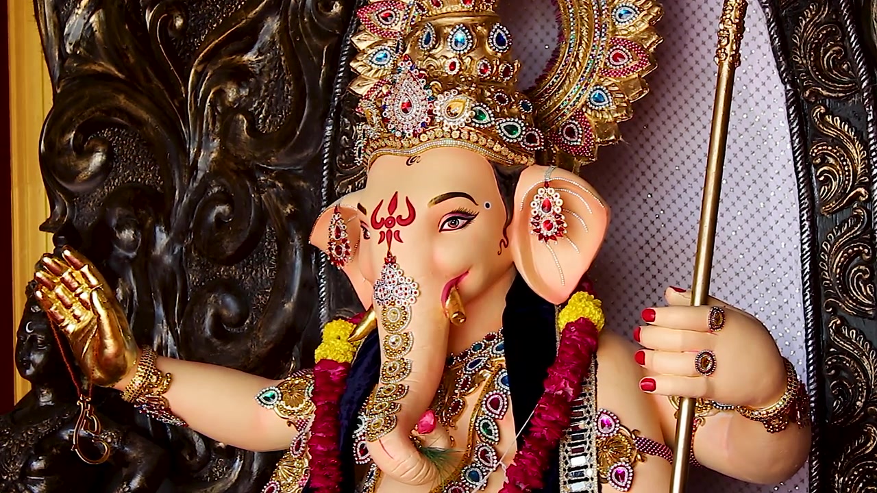 Primo piano del volto dell'idolo di Ganesha, con mano alzata dorata e zanna, durante il festival di Ganesh Chaturthi in India