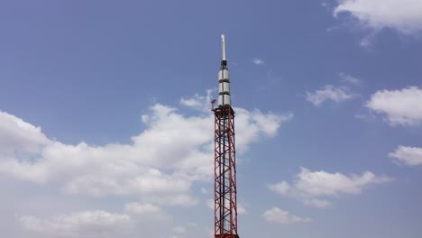 Una-Torre-De-Comunicaciones-Contra-Un-Cielo-Azul-Con-Nubes-Dispersas---Vista-De-Paralaje-En-órbita