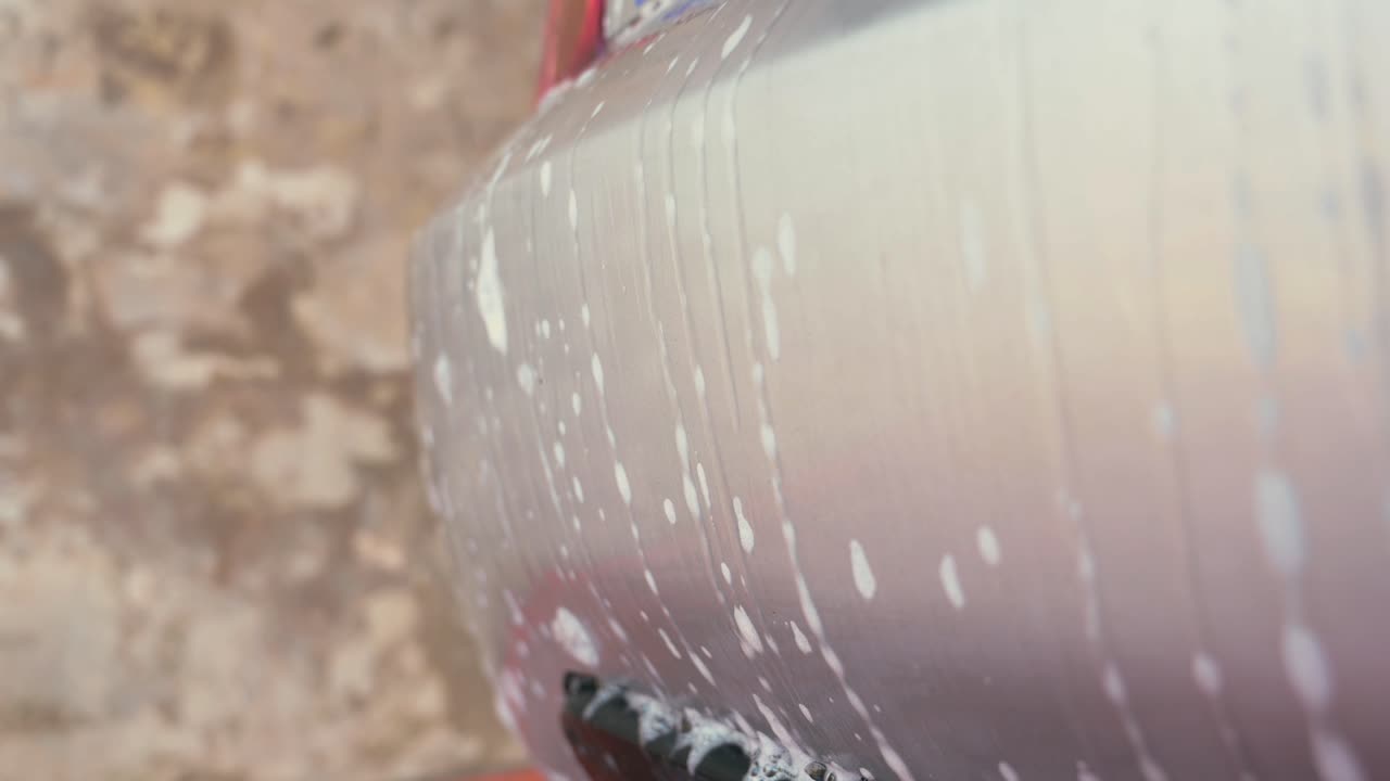 agua y espuma de jabón goteando por la parte trasera de un coche que se está lavando